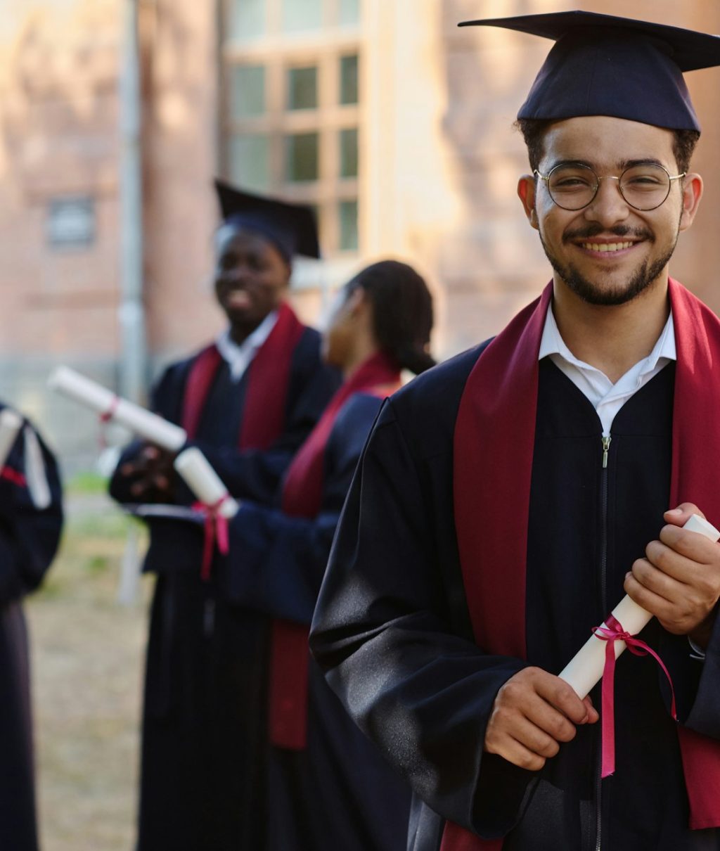 Student in graduation gown standing with diploma
